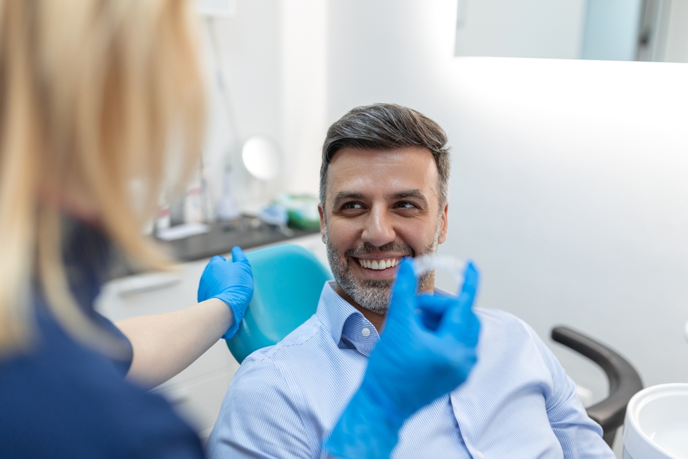 Dental assistant showing a patient an Invisalign clear aligner at Plaza Pointe Dental Specialists