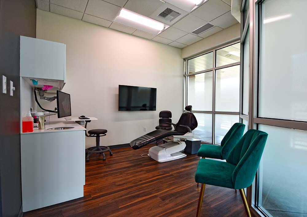 Bright dental treatment room with green guest chairs