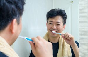 man brushing his teeth in the mirror
